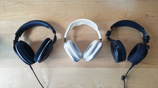 Three headphones in a row on a desktop. 