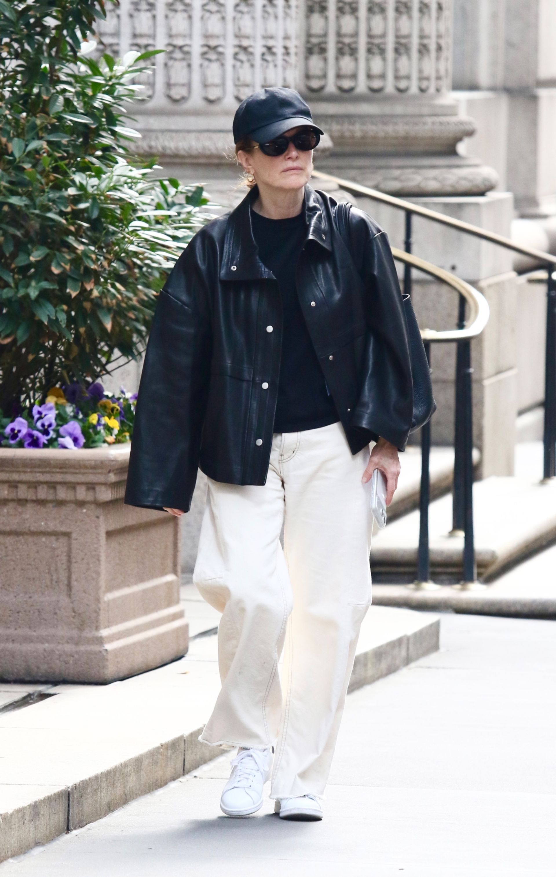 Julianne moore wears a baseball cap, black tee, leather jacket, ecru jeans, and white sneakers.
