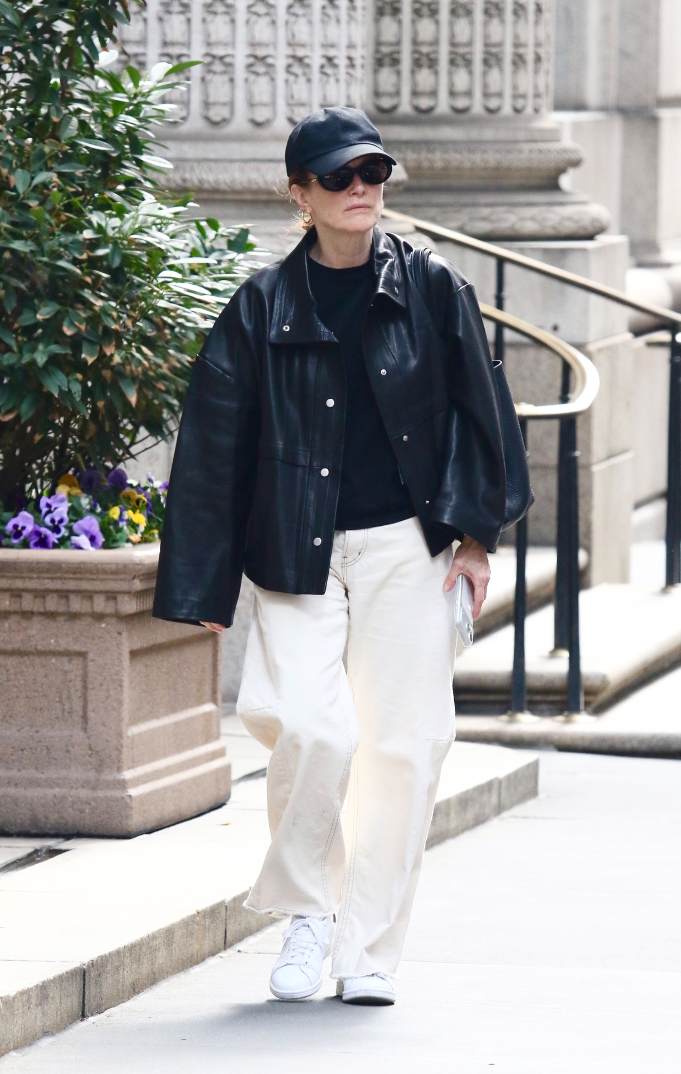 Julianne Moore wears a baseball cap, black tee, leather jacket, ecru jeans, and white sneakers.