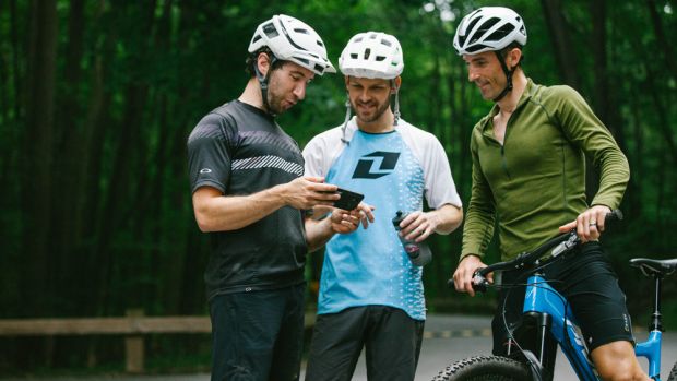 Cyclists looking at Strava on a phone