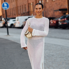 woman wearing a white dress and a gold bag and flip-flops in Helsinki. 