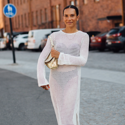 woman wearing a white dress and a gold bag and flip-flops in Helsinki. 