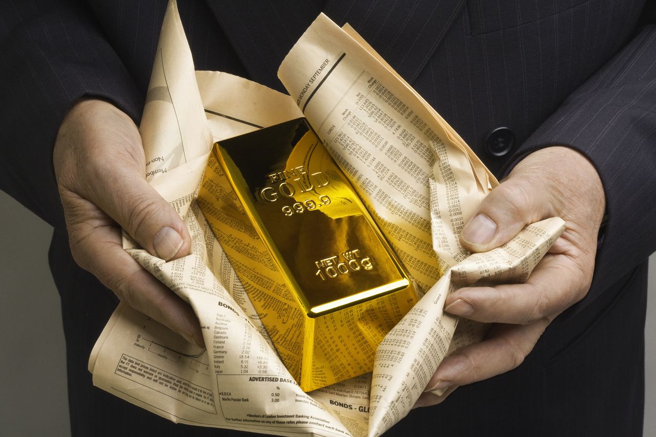 Businessman with gold bar wrapped in newspaper, like fish and chips.