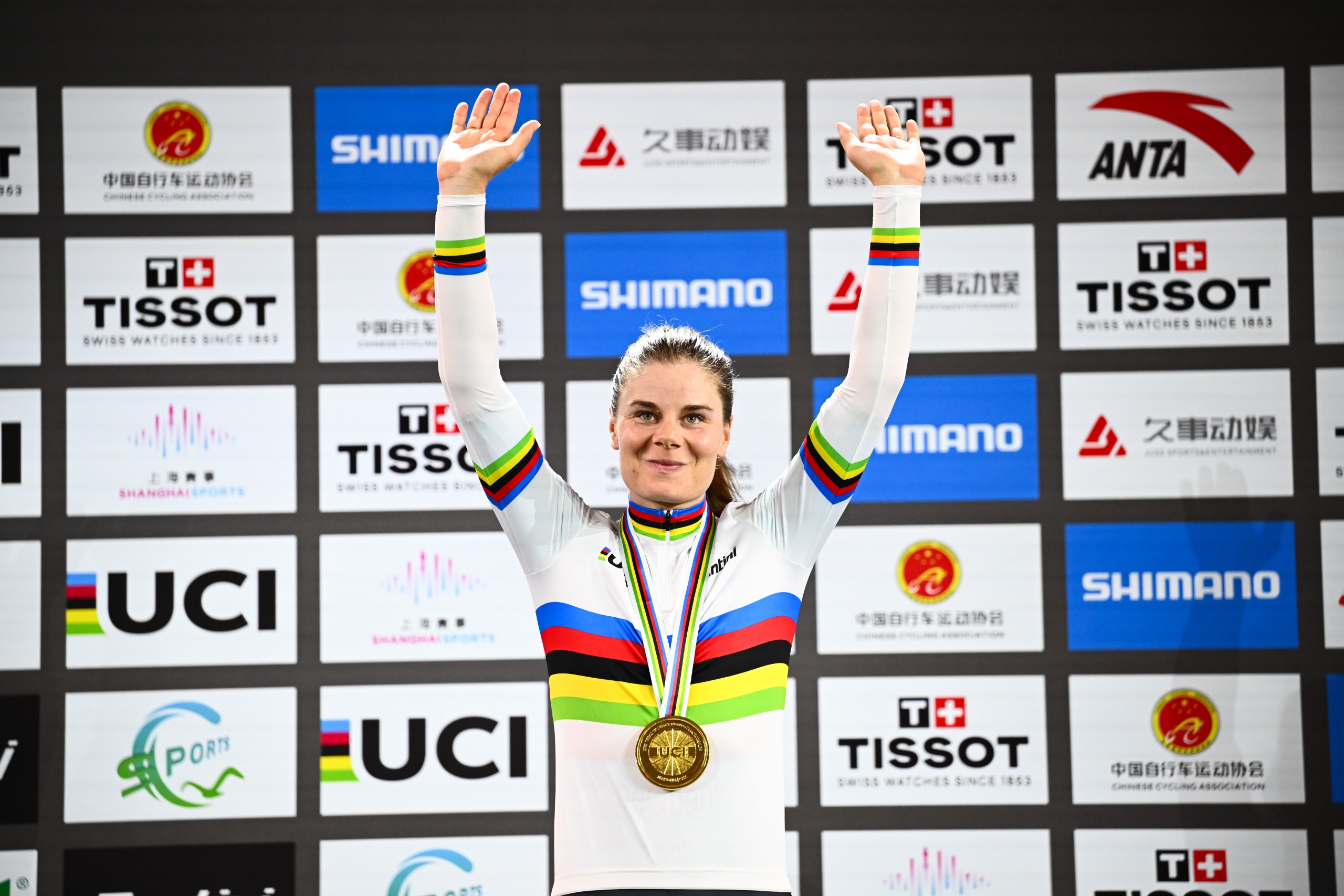 Lotte Kopecky in a rainbow jersey with her arms in the air