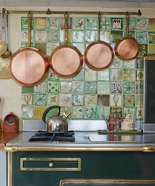 tiled patterned backsplash in a country rustic farmhouse kitchen with green range cooker and copper cooking pans - Credit-tiled-backsplash-Future