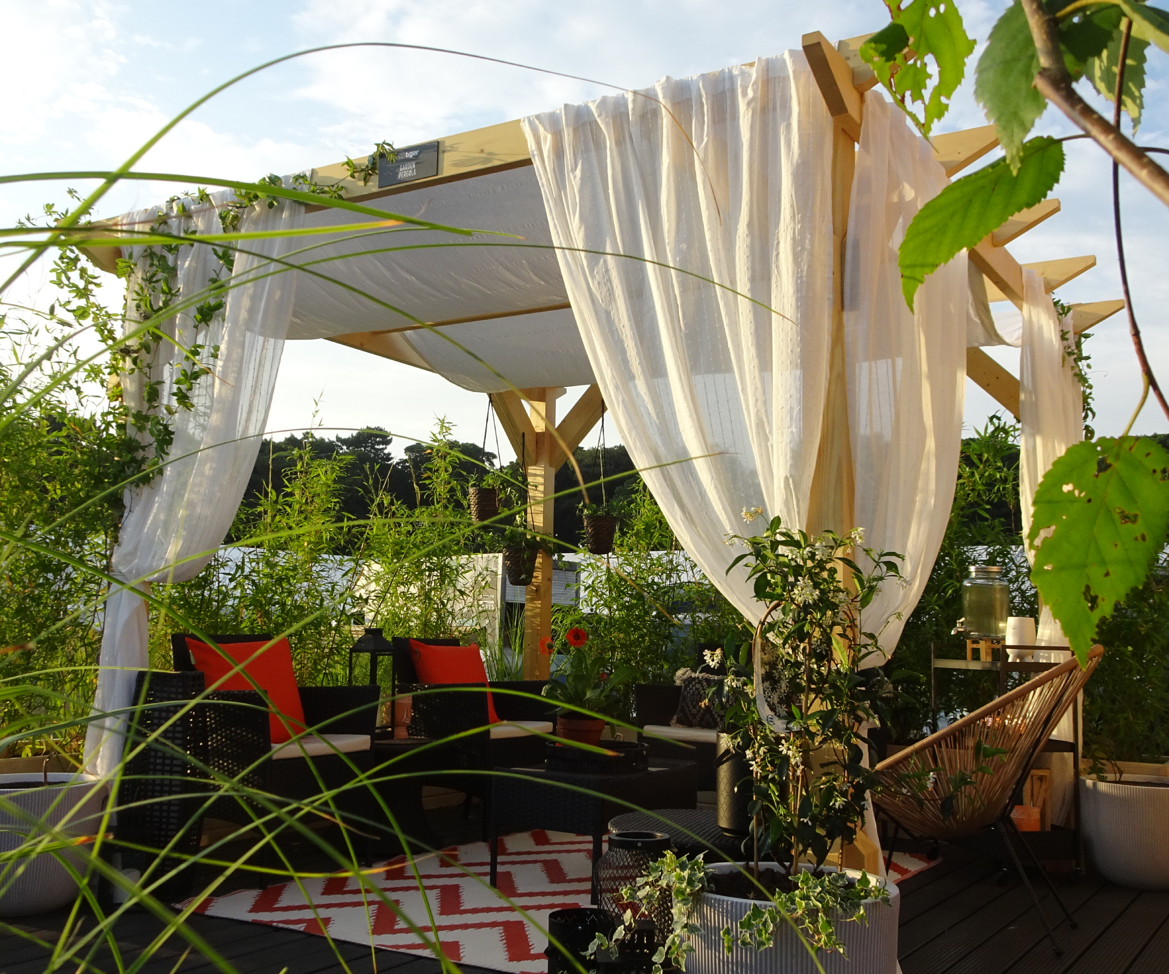 wooden pergola with white sail shade and draped fabric around supports