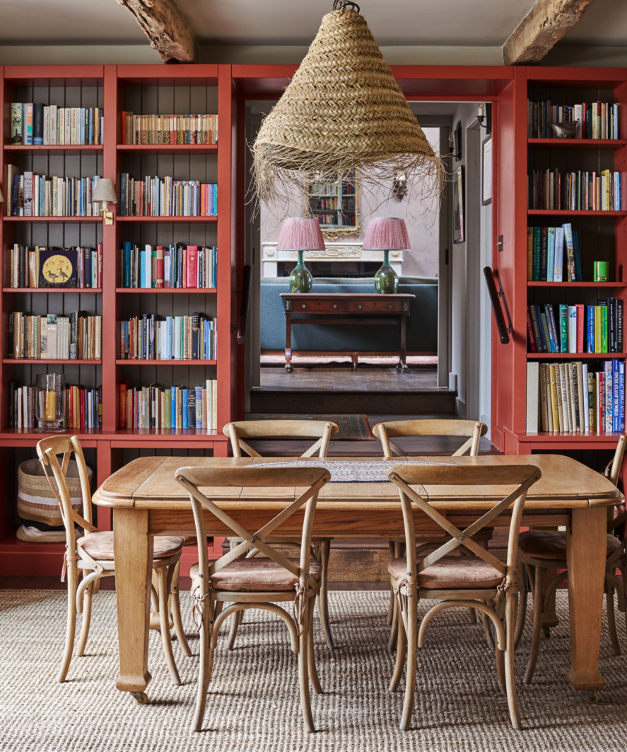 Wooden dining table with red painted bookshelves in the background