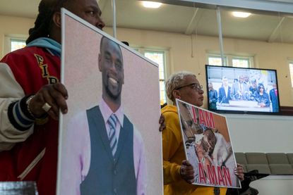  Activists hold photos of Tyre Nichols as attorney Ben Crump speaks on a monitor