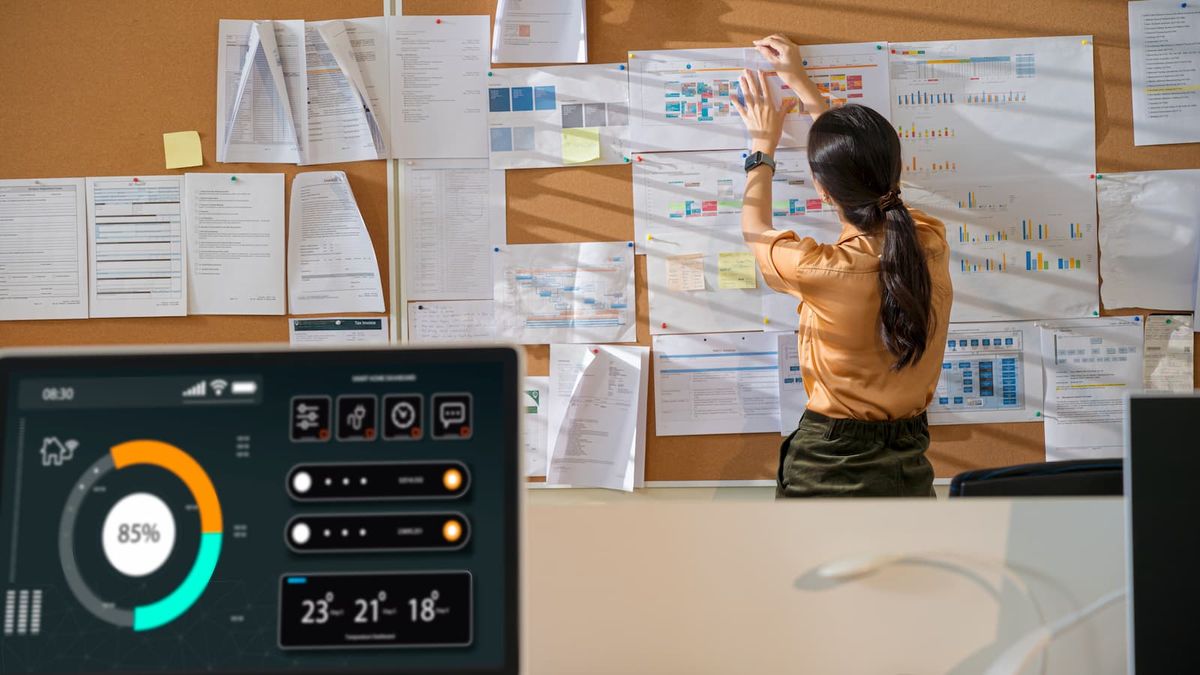 A smart meter with a woman in the background plotting things onto a board