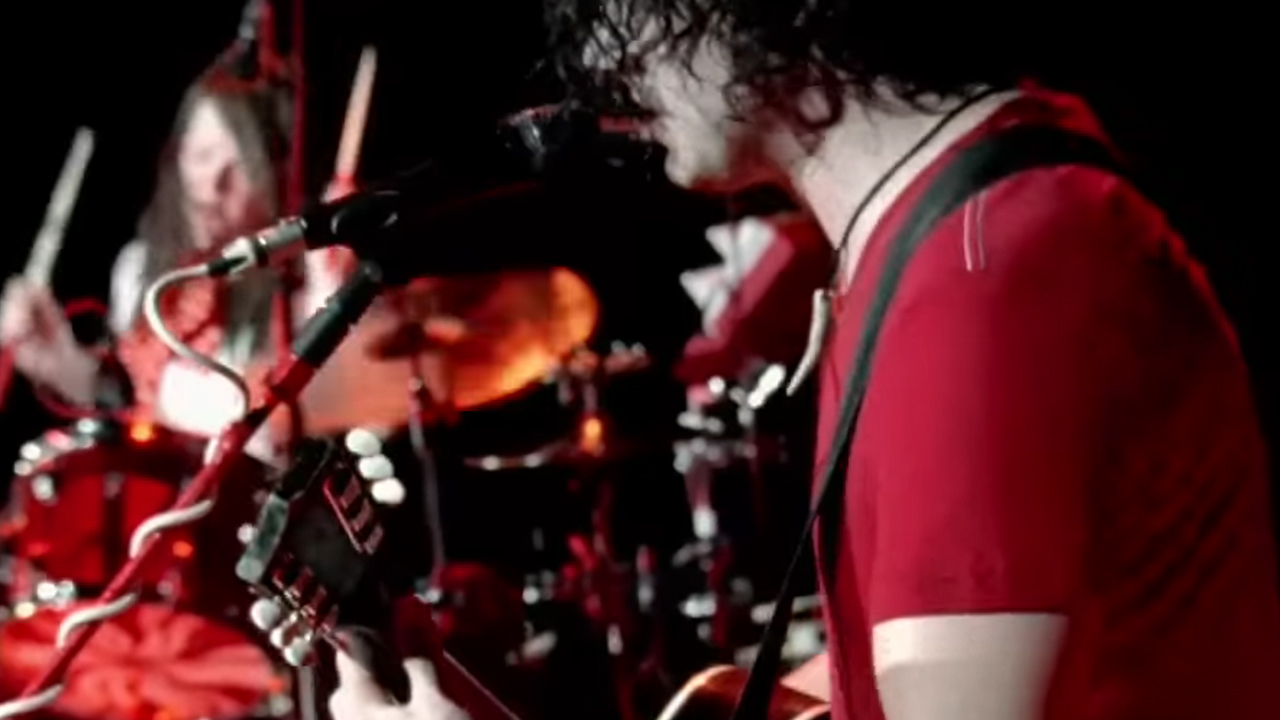 Jack White and Meg White where red and white on stage performing with Jack in the foreground