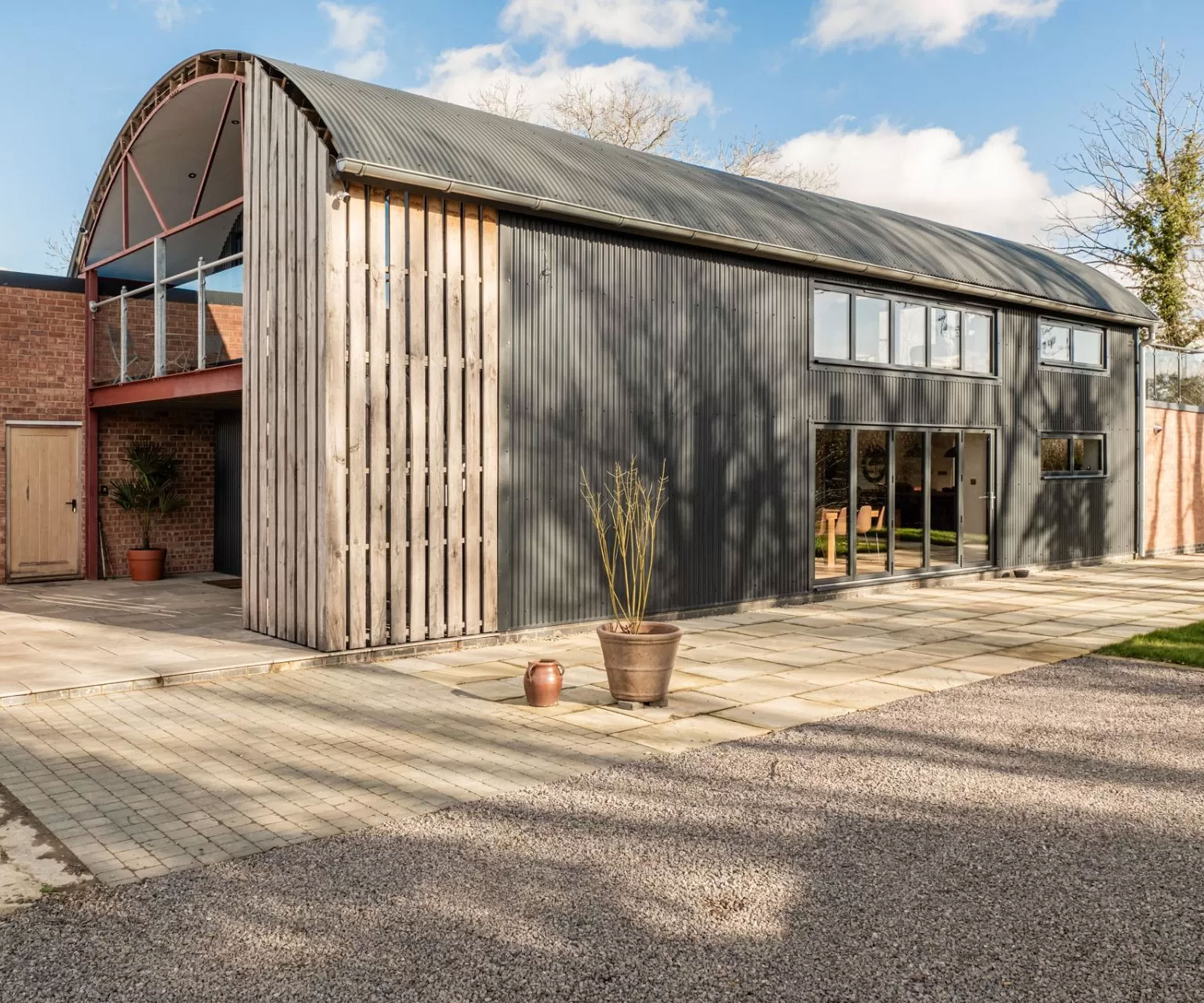 Dutch barn conversion with corrugated metal and timber cladding