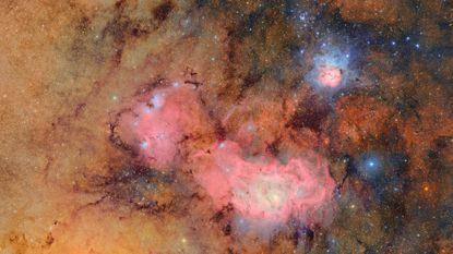 Clouds of pink and gold are seen amidst a deep space background