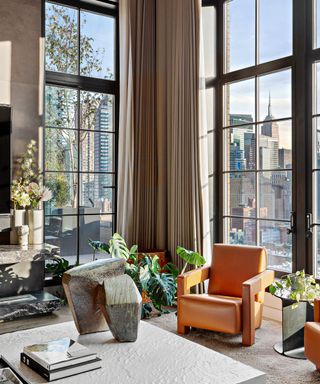 Trevor Noah's Penthouse – corner windows in the living room behind a statement orange arm chair
