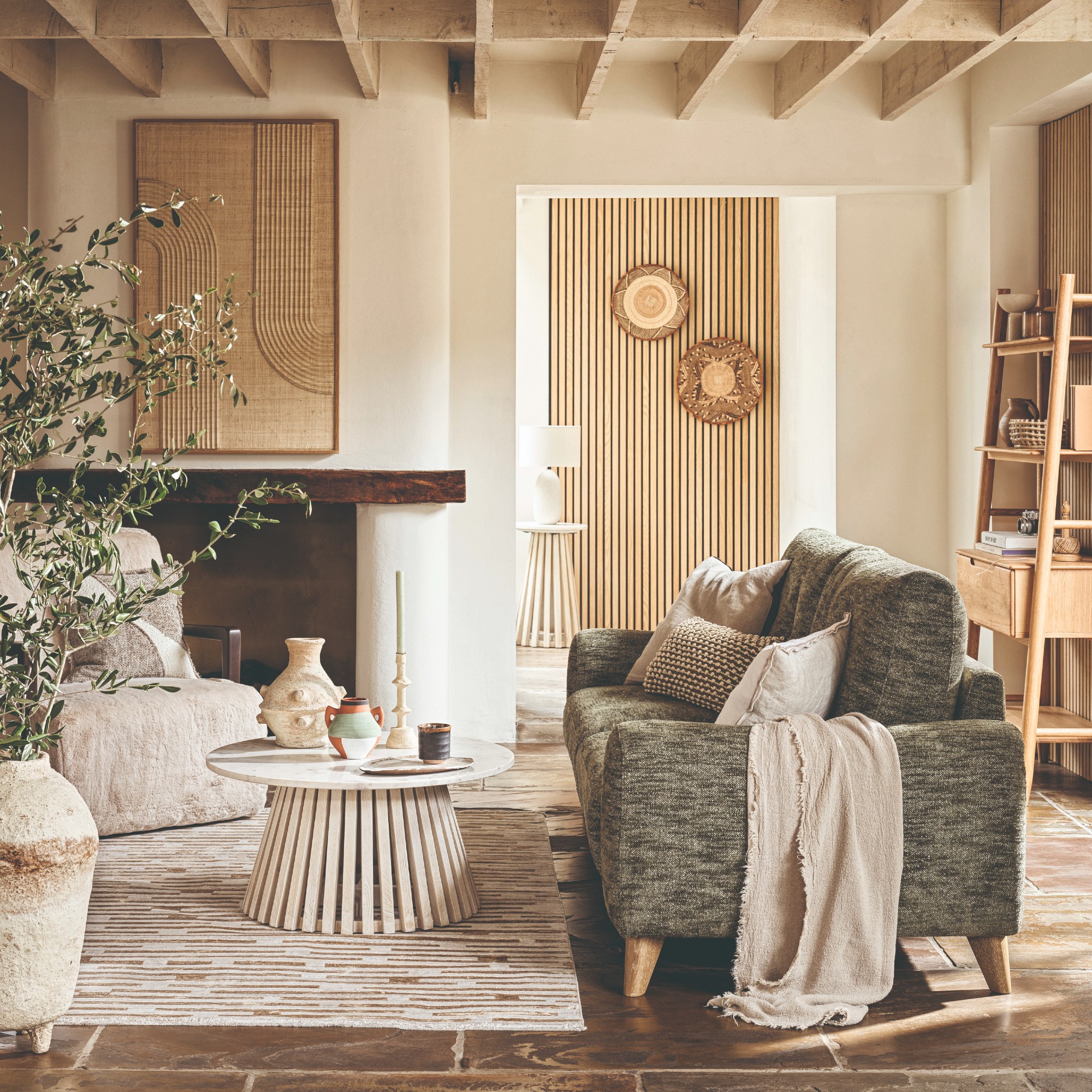 A white cosy living room with an earthy green sofa and a lot of texture through home accessories and pieces of furniture
