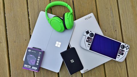 Surface Pro 8, Steam Deck, Surface Duo 2, and other tech piled on a deck outdoors.