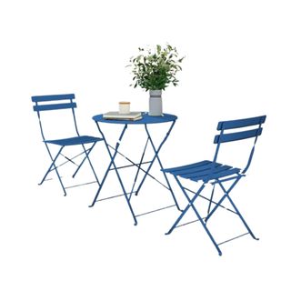 A dark blue bistro set with two metal folding chairs and a circular table with a potted plan and magazine on top of it
