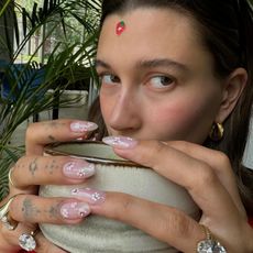 Hailey Bieber taking a selfie drinking tea with cherry blossom nails