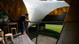 A photographer stands inside the 2014 Serpentine Pavillion, designed by Chilean architect Smiljan Radic, at the Serpentine Gallery in Hyde Park, central London, on June 24, 2014.AFP PHOTO / L