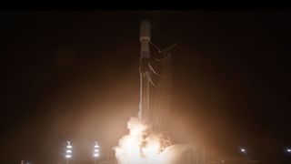 a black and white rocket launches into the night sky, the thrust from its engines casting light on the launch pad.