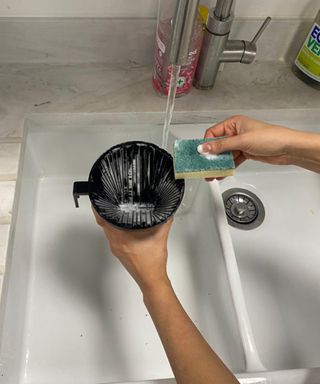 Christina Chrysostomou cleaning the Technivorm Moccamaster Select filter basket in sink with Ecover dish soap and sponge