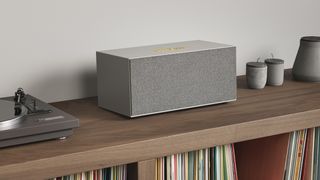 Audio Pro C20 in grey sitting on a wooden stand