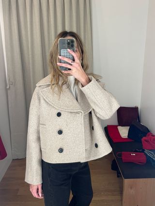 Eliza Huber in the dressing room at Madewell's new SoHo flagship in New York wearing a cropped peacoat-style cropped jacket, black jeans, a white T-shirt, and studded boots.