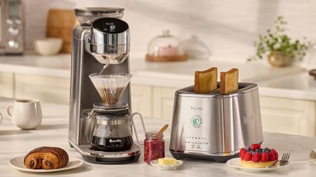 A silver Breville Spiral Luxe&trade; Auto Pour-Over Coffee Maker beside a matching toaster, on a white kitchen counter