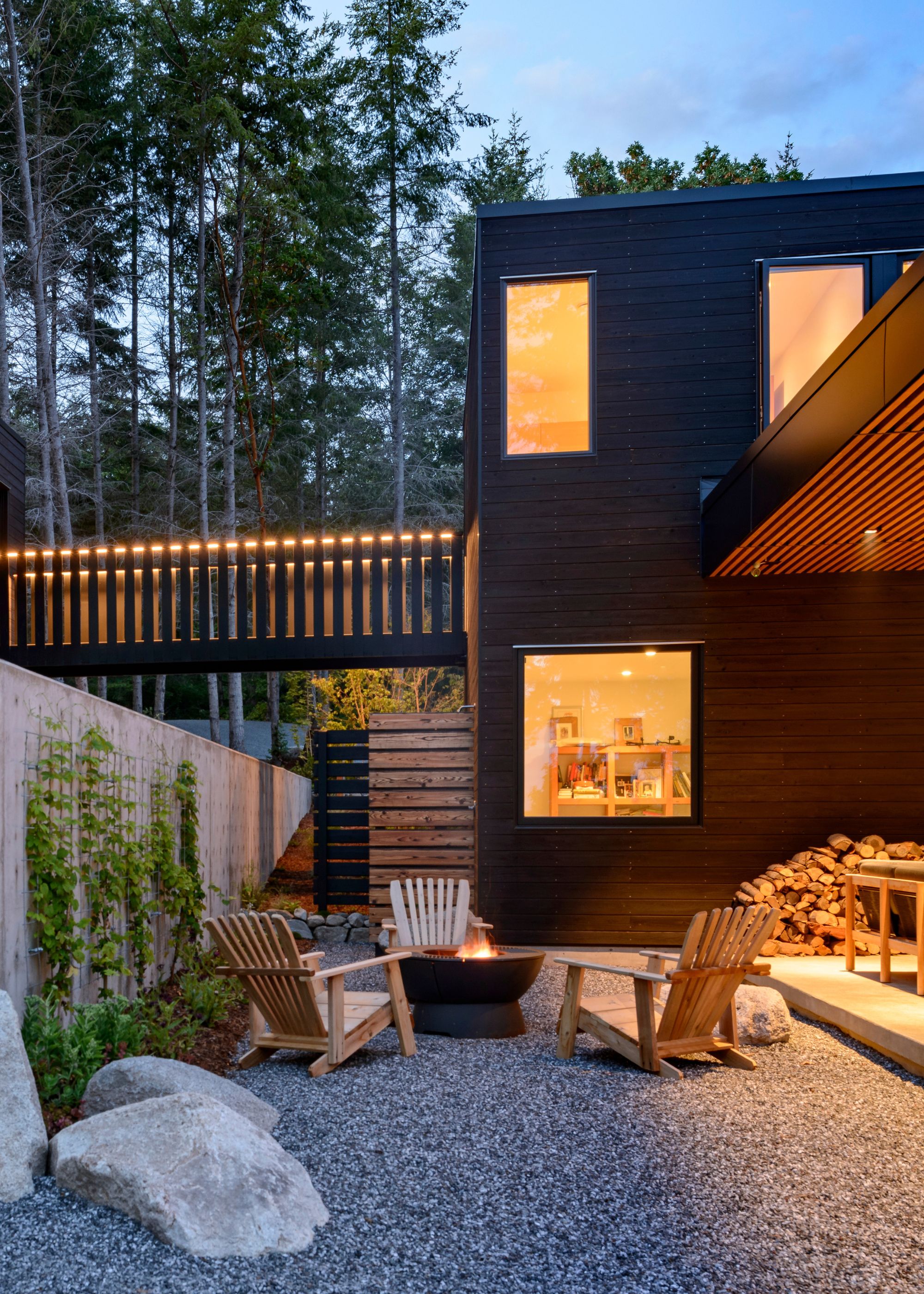 A group of chairs places around a firepit in a patio of a home. You can also see the exterior of the home as well as a little glimpse inside the home.