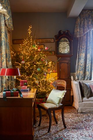 living room in old house with Christmas tree by a desk