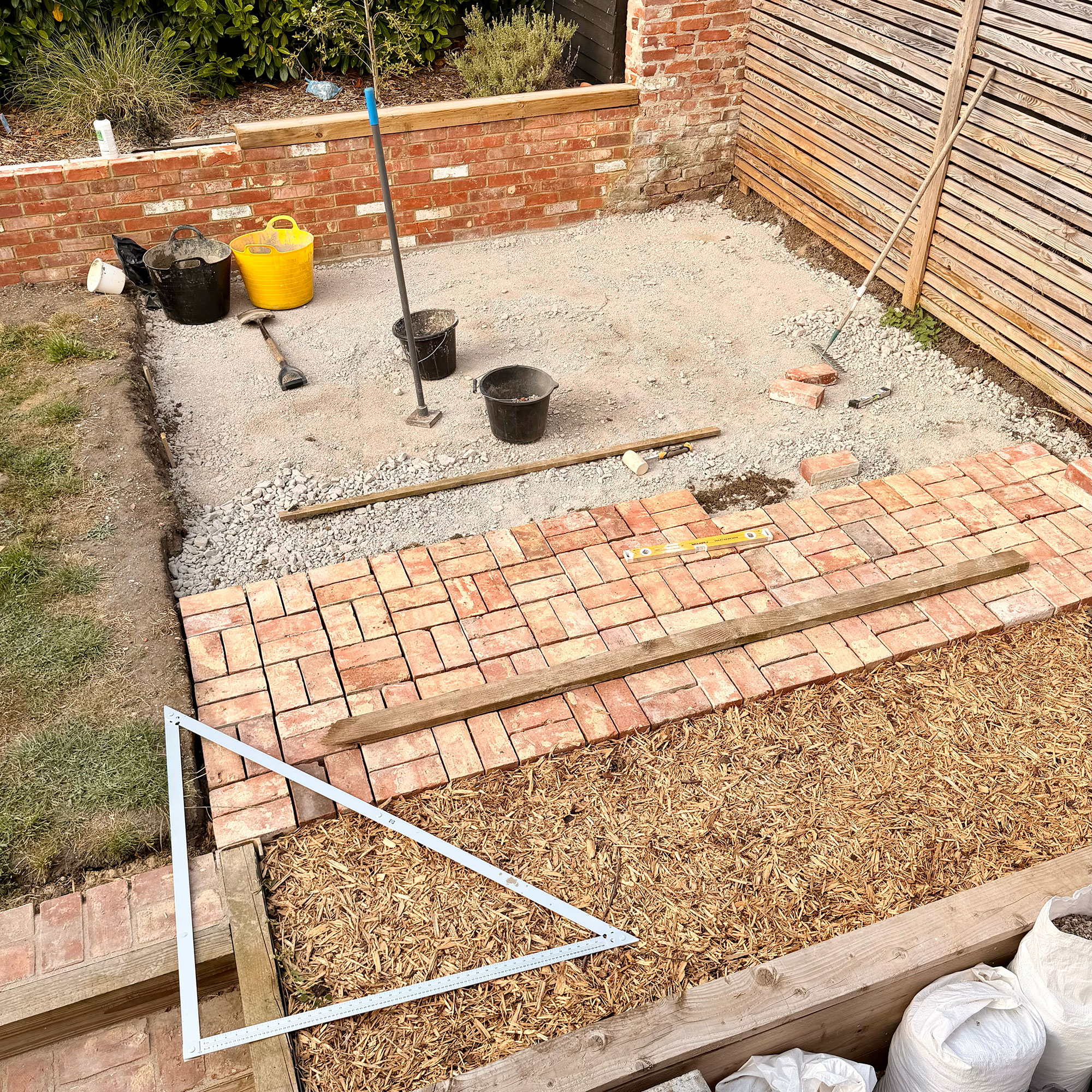 Area of garden mid being turned into patio, with one third laid with bricks