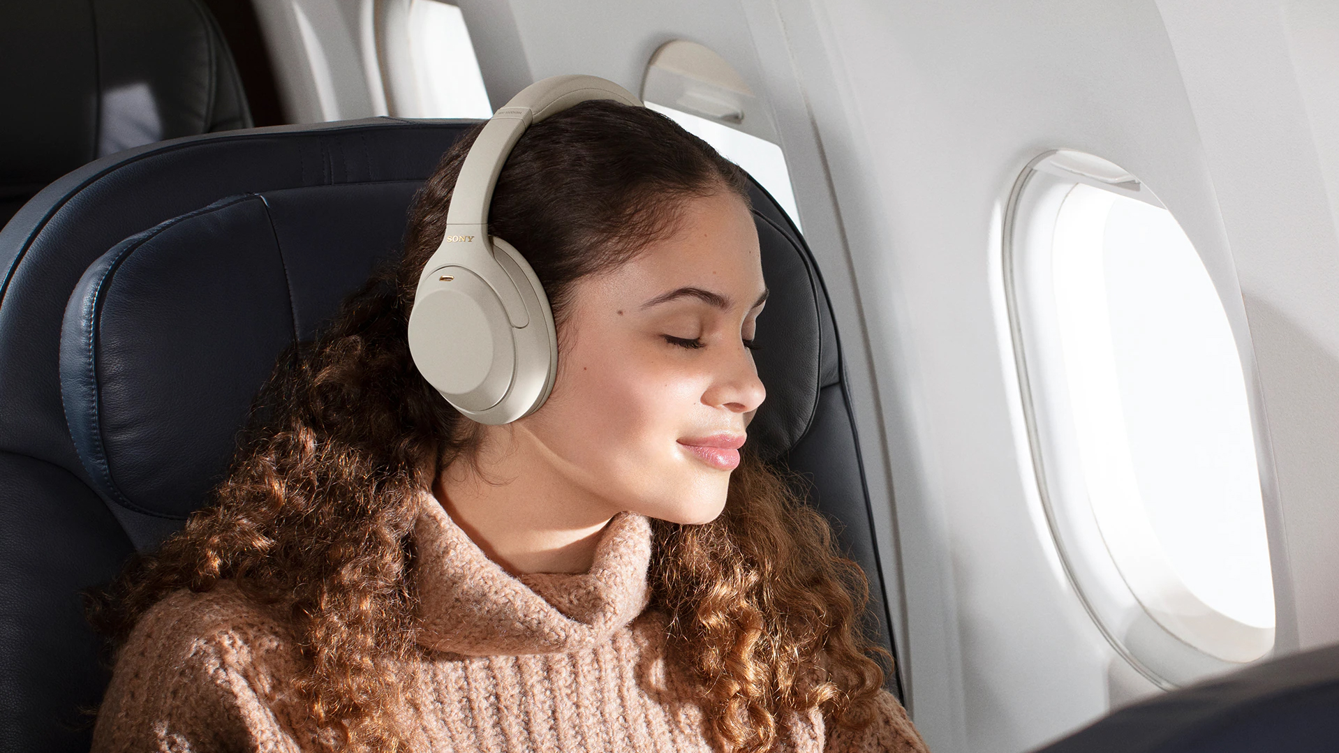 Sony WH-1000XM4 used by a woman on a plane