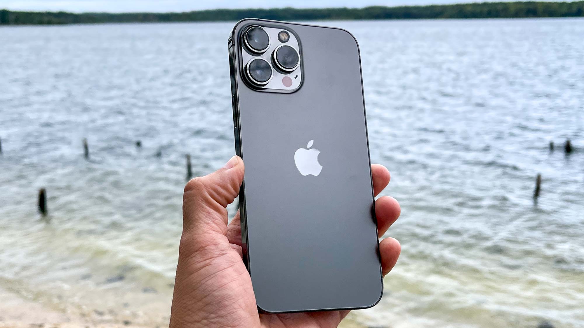 iPhone 13 Pro Max in grey, held in front of water