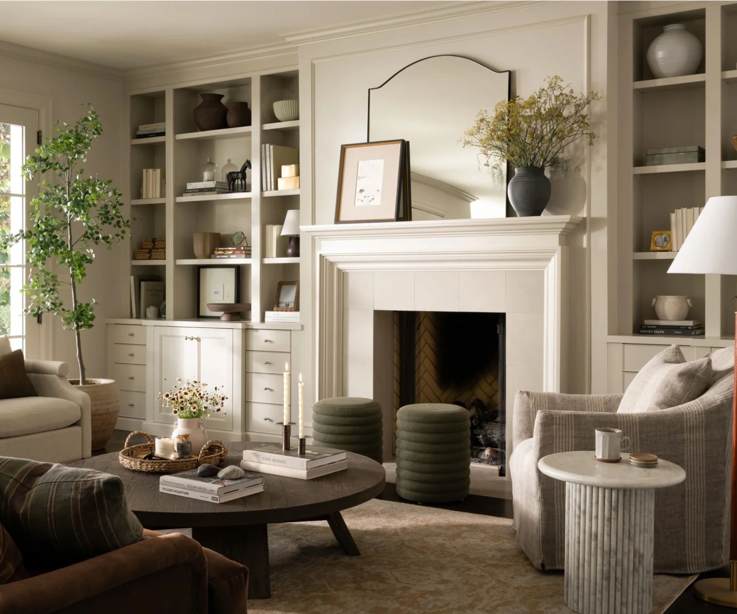 neutral living room with a large fire, large black wooden round coffee table and two swivel chairs