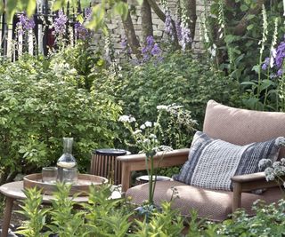 An outdoor table and chair surrounded by purple foxgloves and green planting