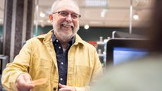 Smiling senior man giving credit card to cashier at supermarket checkout counter