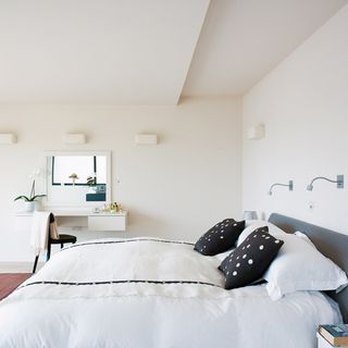 bedroom with white walls and bed with white and grey pillows