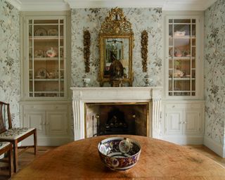 dining room with decorative fabric walling by bennison with grand fireplace and mantel mirror