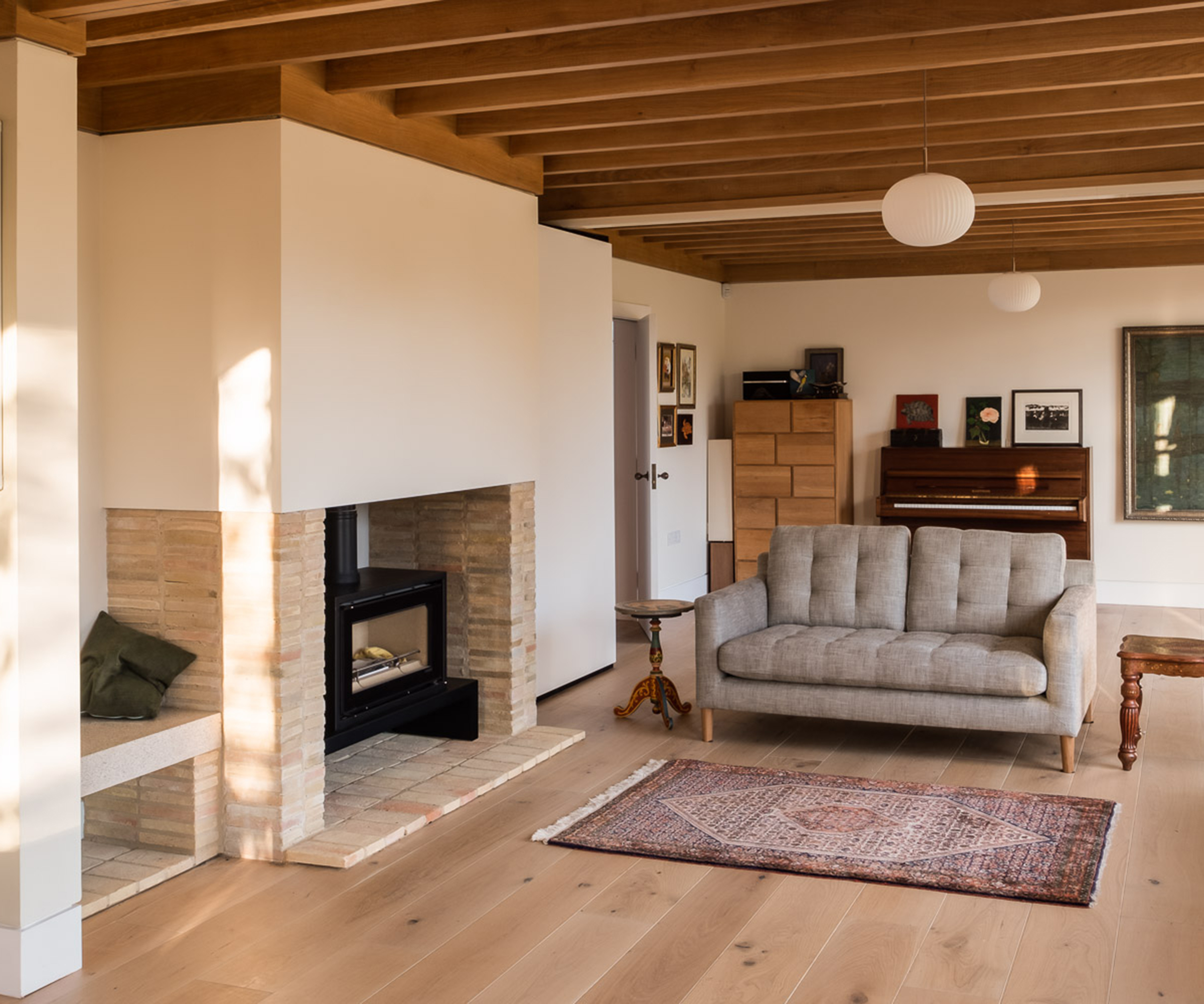a grey sofa and rug next to a wood burning stove in a new living room