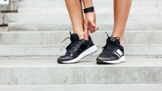 Person adjusting running shoes on steps