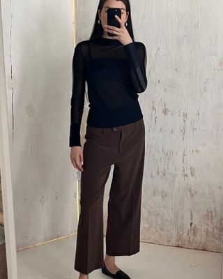 Woman wears vintage brown pleated pants and a black long-sleeve shirt.