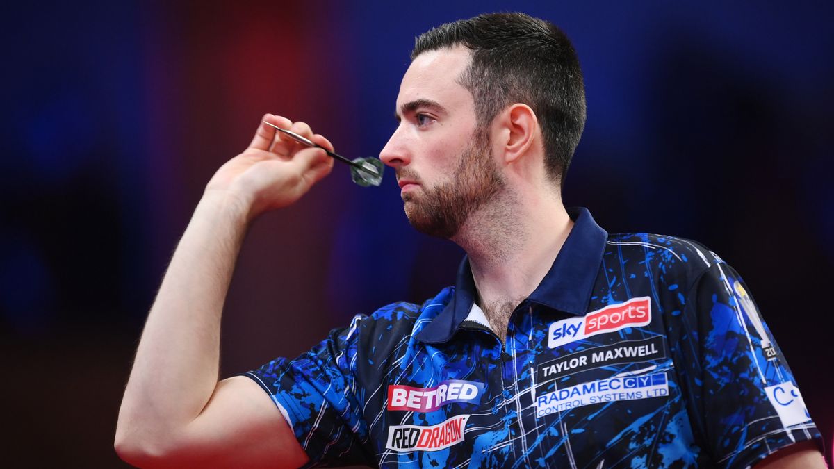 Luke Humphries throws a dart in profile wearing a blue patterned shirt