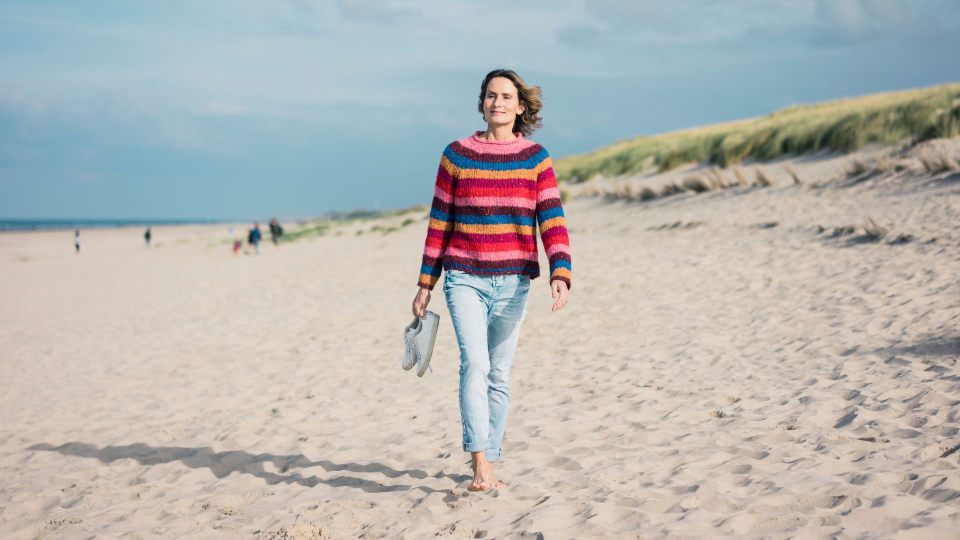 Woman walking along a beach barefoot