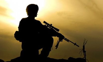 A U.S. army soldier kneels during sunset security patrol in Afghanistan.