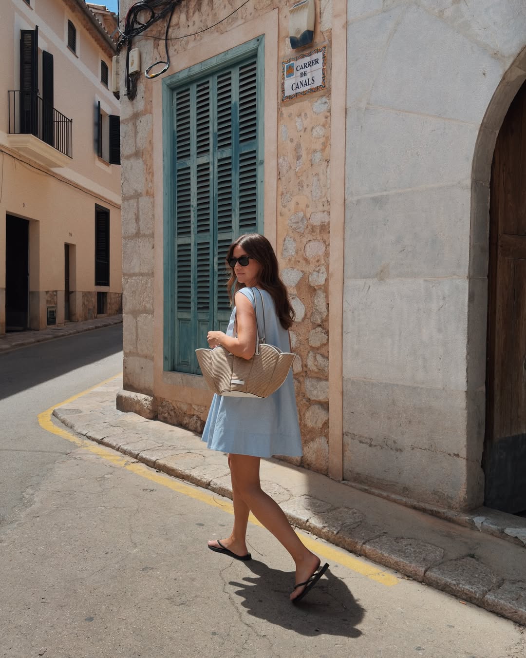 @kimturkington_ wears a light blue shift dress, black flip-flops and a basket bag
