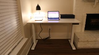 Branch Standing Desk next to a fireplace with a computer and lamp on top
