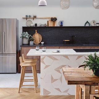 modern kitchen with black worktop and matching splash back, black tap, marble topped island with tiles on side, wood bar stools, rustic dining table, open shelving, fridge