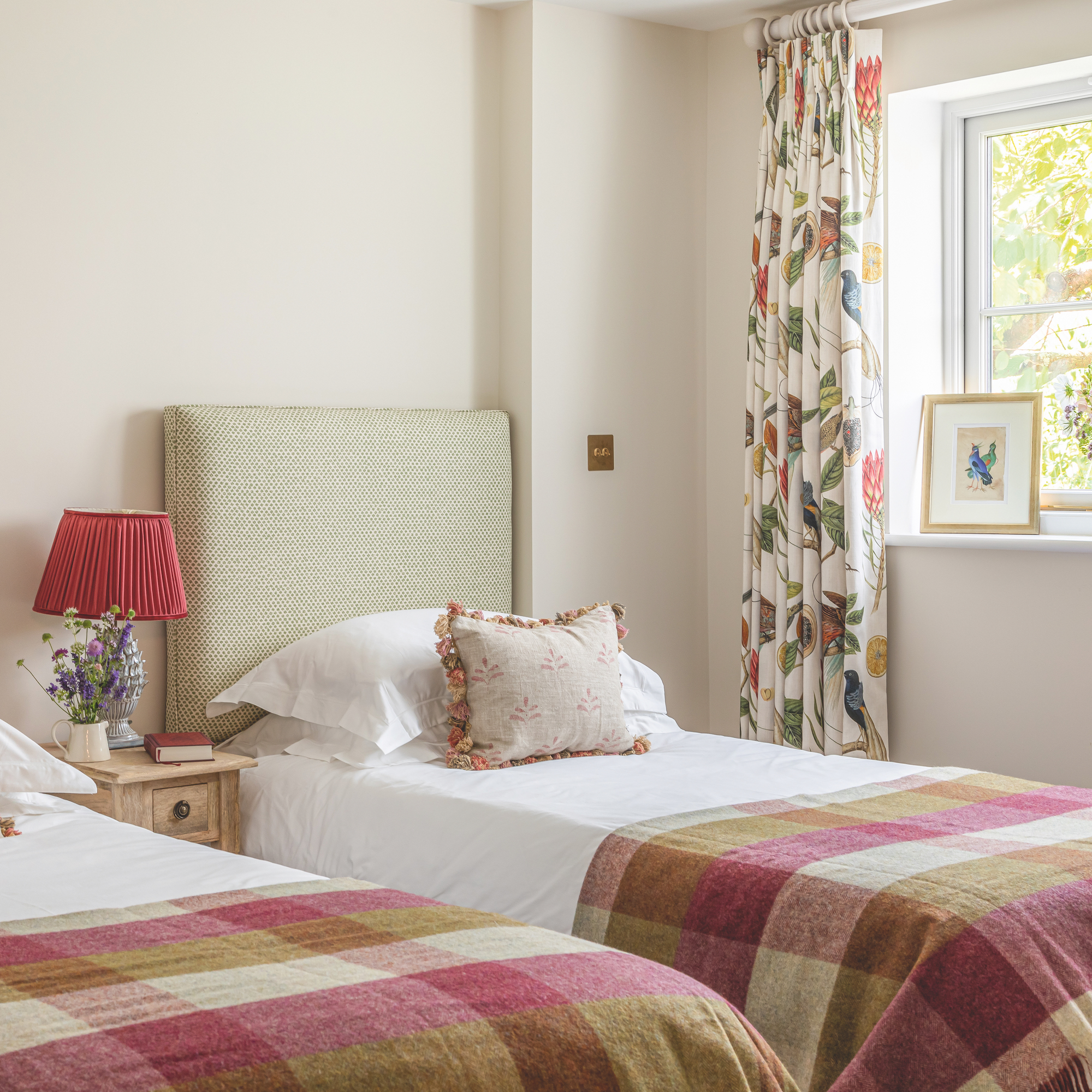 twin bedroom with check blankets on bed and lamp with red shade