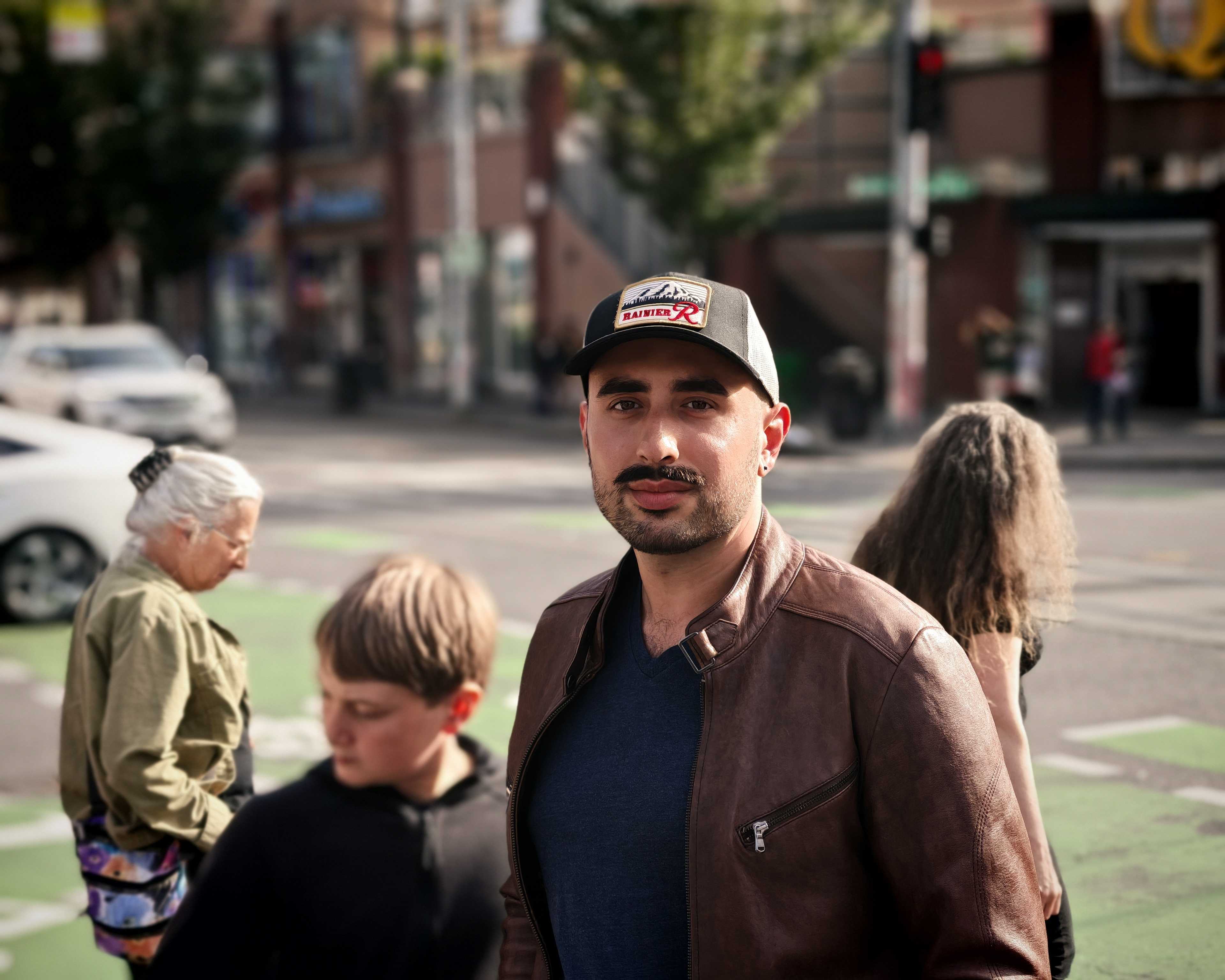 A man looking at the camera on a busy street with people behind him