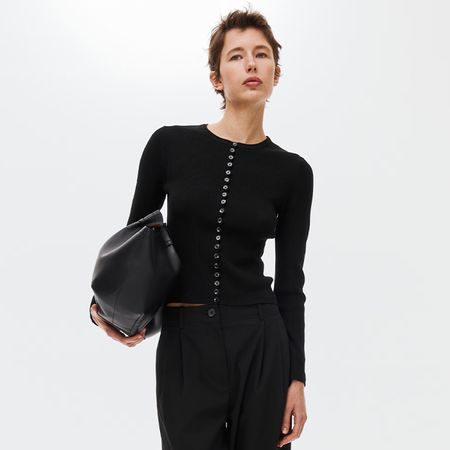 model wears black cardigan, black clutch, and pants.