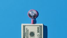 Stethoscope with $100 bills attached, over blue background